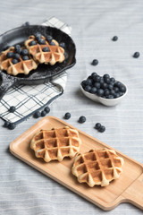 Belgium waffle with blueberry topping in the pan on the tablecloth