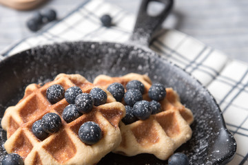 Belgium waffle with blueberry topping in the pan on the tablecloth
