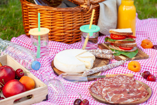 Picnic basket with different snacks on the green grass in the garden