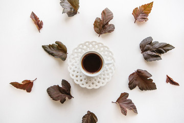 A cup of aromatic espresso or black tea. Nearby lie autumn leaves. Simple minimalistic autumn design.