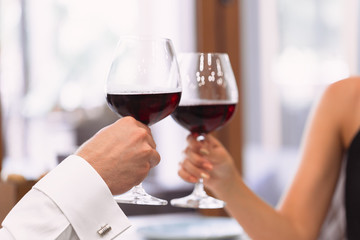 Beautiful young couple with glasses of red wine in luxury restaurant