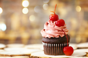 Delicious chocolate cupcake with cherries on blurred background