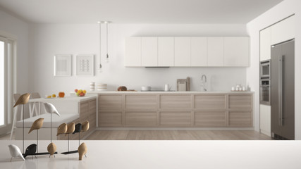 White table top or shelf with minimalistic bird ornament, birdie knick - knack over blurred contemporary scandinavian wooden kitchen, modern interior design