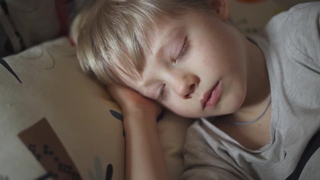 Evening, the boy lies down on the bed and falls asleep.

