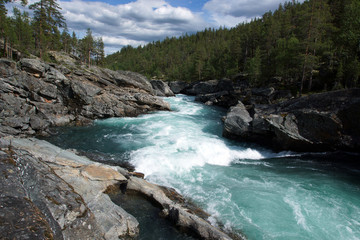 Naklejka na ściany i meble A stormy river stream with noise flows through the rocks and forest in Norway, clear transparent blue water