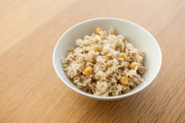 brown rice on the bowl, wood table.