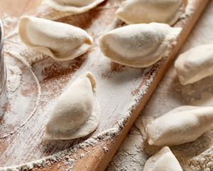 Raw russian dumplings with flour on table