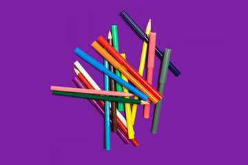 pile of different multicolored bright plastic felt pens and pencils lying on a yellow background. concept of office or educational accessories
