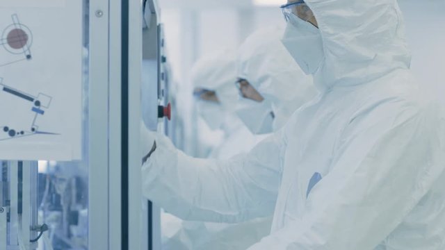 On a Factory Team of Scientists in Sterile Protective Clothing Work on a Modern Industrial 3D Printing Machinery. Pharmaceutical, Biotechnological and Semiconductor Creating / Manufacturing Process.