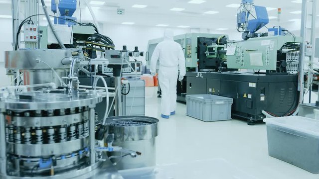On a Factory Scientist in Sterile Protective Clothing Work on a Modern Industrial 3D Printing Machinery. 