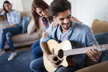 Young handsome man playing guitar for his girlfriend