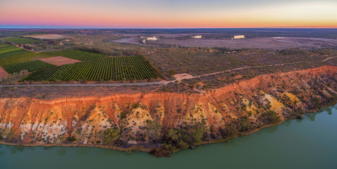 Orange sandstone erosion layers and agricultural fields at Murtho, Riverland, Australia at dusk - aerial panorama
