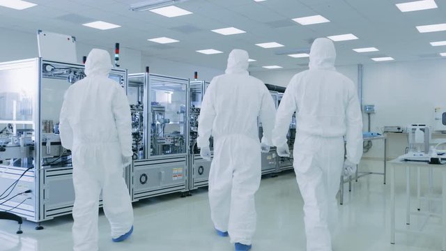 Gliding Shot through Sterile Pharmaceutical Manufacturing Laboratory where Scientists in Protective Coverall's Do Research, Quality Control and Work on the Discovery of new Medicine. 