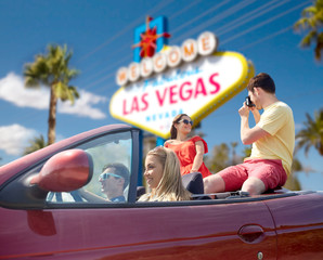 summer holidays, road trip and travel concept - happy friends driving in convertible car and taking...