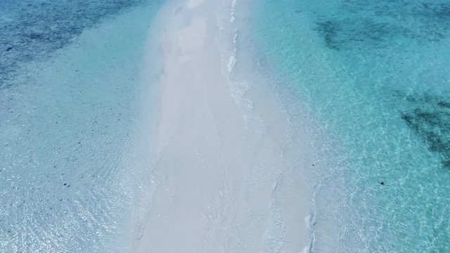 Cinematic reveal shot aerial view of long beach shoreline in a beautiful small beach island with white sand and pristine clear blue turquoise water