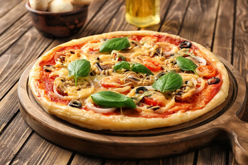 Board with tasty pizza on wooden table