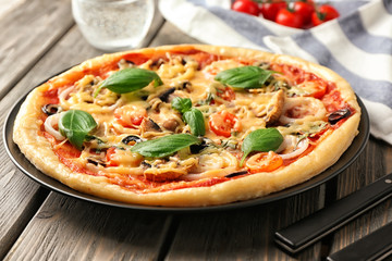 Plate with tasty pizza on wooden table
