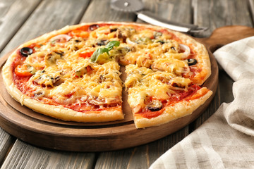 Board with tasty pizza on wooden table