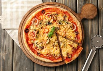 Board with tasty pizza on wooden background, top view