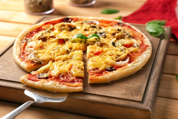 Board and shovel with tasty pizza on wooden table