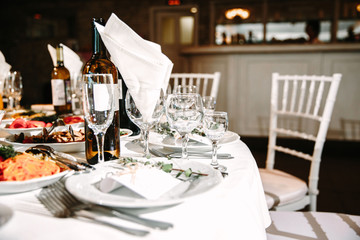 Wedding. Banquet. The chairs and round table for guests, served with cutlery, flowers and crockery and covered with a tablecloth