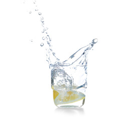 Glass with splashing water and sliced citrus fruit on white background