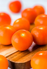 A group of small cherry tomatoes on a mini wooden chopping board