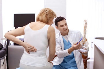 Orthopedist showing spine model to patient in hospital