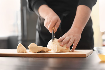 Baker cutting dough on kitchen table
