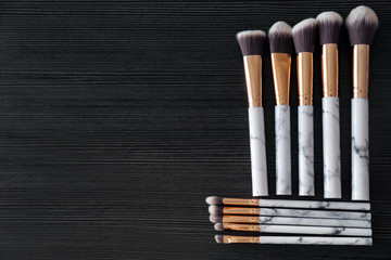Makeup brushes for applying decorative cosmetics on dark wooden background