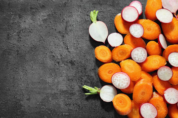 Ripe sliced radish and carrot on gray background, top view