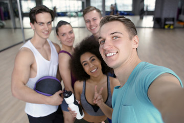 Group of sportive people taking selfie in gym