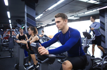 Young man training on special sport equipment in gym