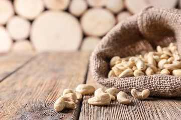 Bag with tasty cashew nuts on wooden table
