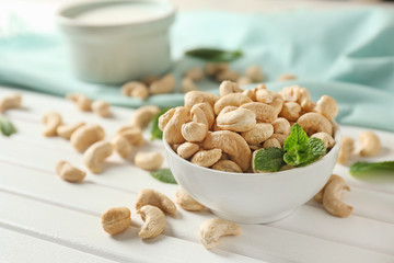 Bowl with tasty cashew nuts on wooden table