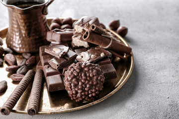 Pieces of delicious chocolate with coffee on metal tray