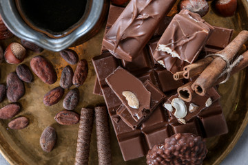 Pieces of delicious chocolate with coffee on metal tray, top view