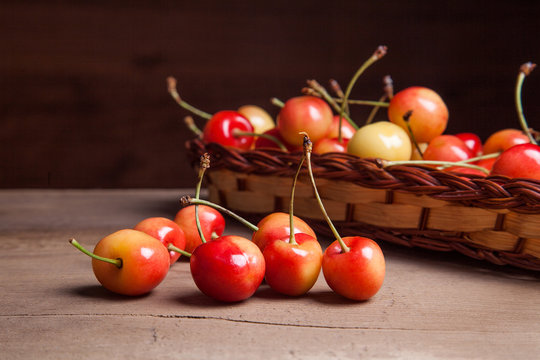 Yellow sweet cherry in basket on wooden background.