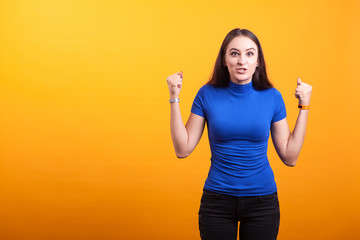 Angry woman yelling in studio over yellow backgound