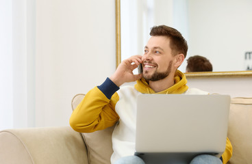 Freelancer talking on phone while using laptop at home