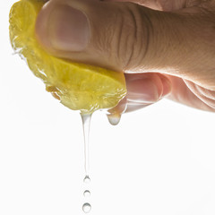 close up Human hand squeezing half of lemon on white background