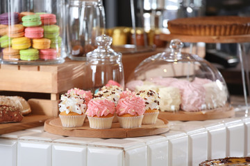 Delicious cupcakes on wooden board in bakery