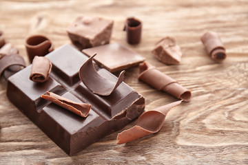 Piece of chocolate with curls on wooden table