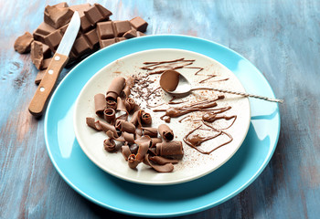 Plate with delicious chocolate curls on table