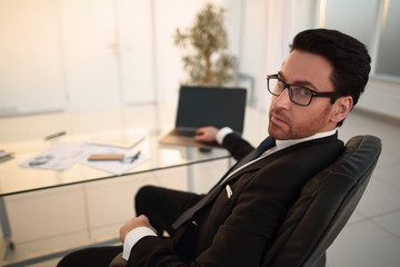 businessman sitting at his Desk and looking at the camera