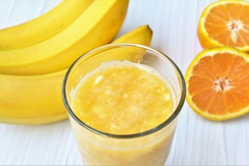 Banana orange smoothie in a glass, closeup.