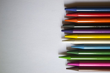 Fototapeta premium Multicolored pencils on white background. A palette of pencils on a table, close up.