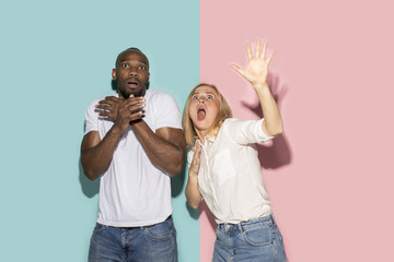 Portrait of the scared couple on pink and blue studio background