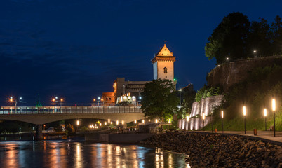 Fototapeta na wymiar Night panorama of the Narva castle with the tower High Herman, Narva, Estonia. In the foreground is the city promenade and a bridge across the Narova River. The bridge connects Estonia and Russia
