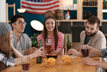 Group of cheerful friends drinking beer in bar